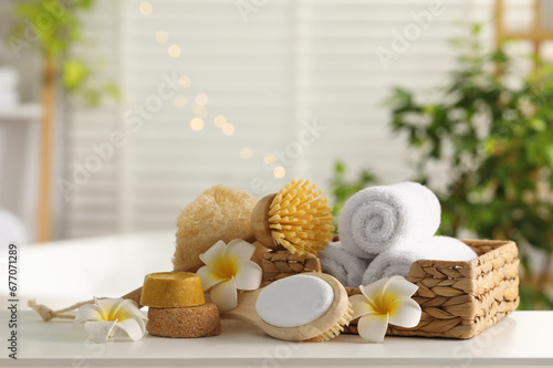 Composition with different spa products and plumeria flowers on white table in bathroom