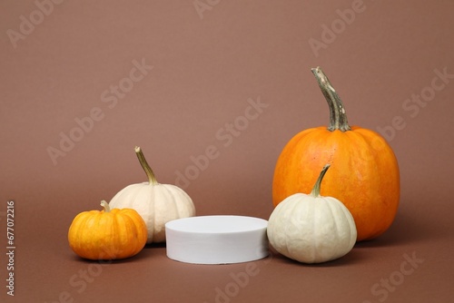 White round shaped podium and pumpkins on light brown background. Autumn presentation for product