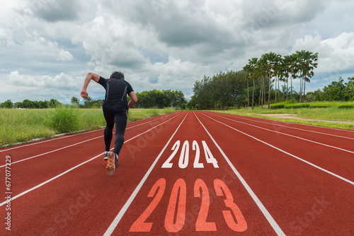 The start into the new year 2024. Start up of runner woman running on nature race track go to Goal of Success. People running as part of Number 2023. Holiday sport and health care Concept