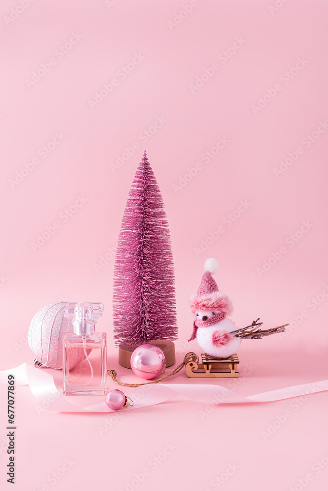 New Year's presentation of the fragrance of women's perfume in a chic bottle on a pink background among decorative New Year's elements. Vertical view. New Year's presentation of the fragrance of women's perfume in a chic bottle on a pink background among decorative New Year's elements. Vertical view.