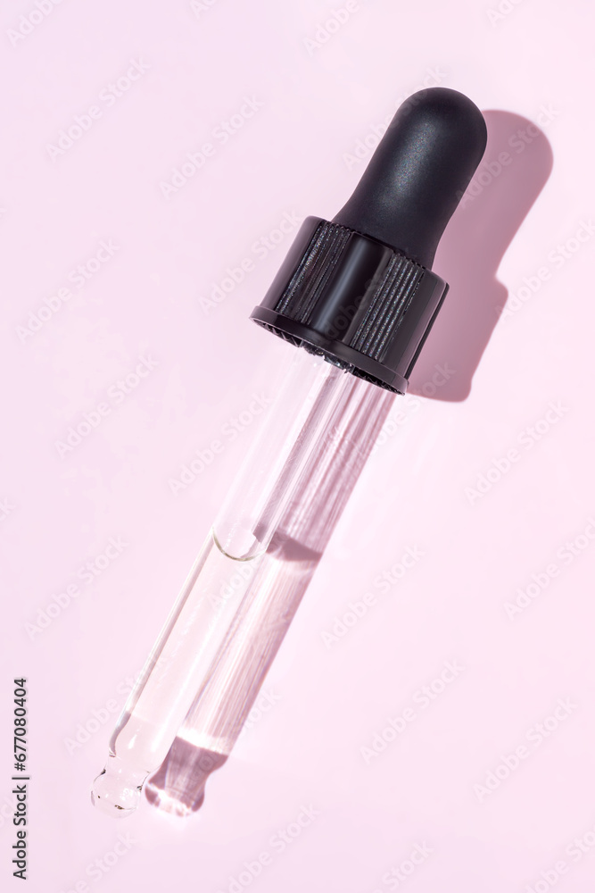 skin care cosmetics. Pipette with oil close-up. Cuticle oil. Oil for the care of nails and hands. A transparent pipette lies on the pink background skin care cosmetics. Pipette with oil close-up. Cuticle oil. Oil for the care of nails and hands. A transparent pipette lies on the pink background