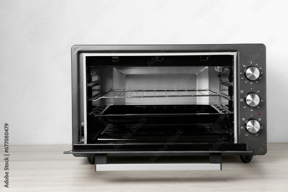 One electric oven on wooden table near light blue wall One electric oven on wooden table near light blue wall