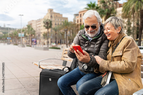 Active senior couple tourists traveling together using cell phone to check hotel restaurant direction
