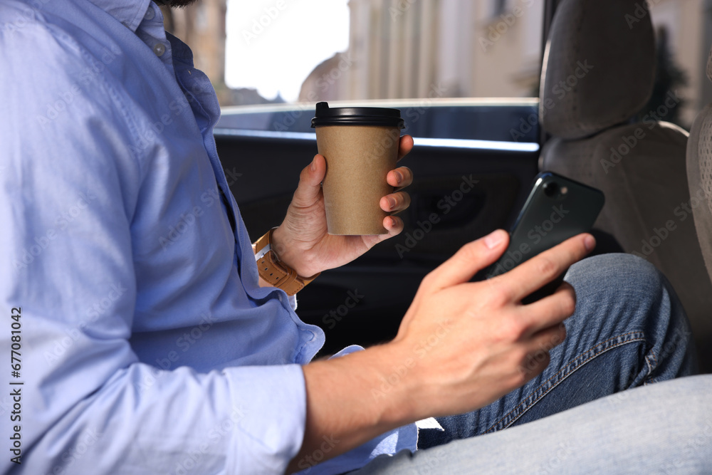 Coffee to go. Man with paper cup of drink and smartphone in car, closeup