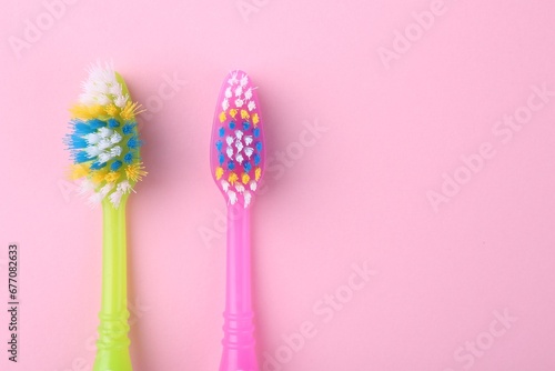 Colorful plastic toothbrushes on pink background, flat lay. Space for text