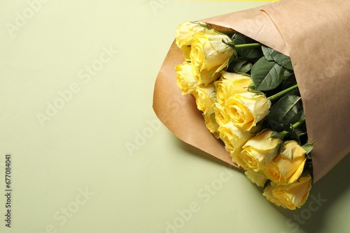 Beautiful bouquet of yellow roses on light green background  above view. Space for text