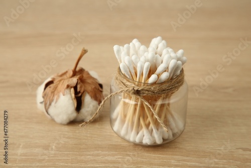 Cotton swabs and flower on wooden table, closeup