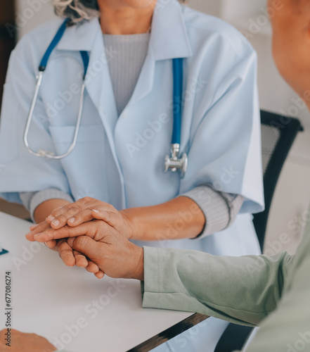 Doctor giving hope. Close up shot of young female physician leaning forward to smiling elderly lady patient holding her hand in palms. Woman caretaker in white coat supporting encouraging old person