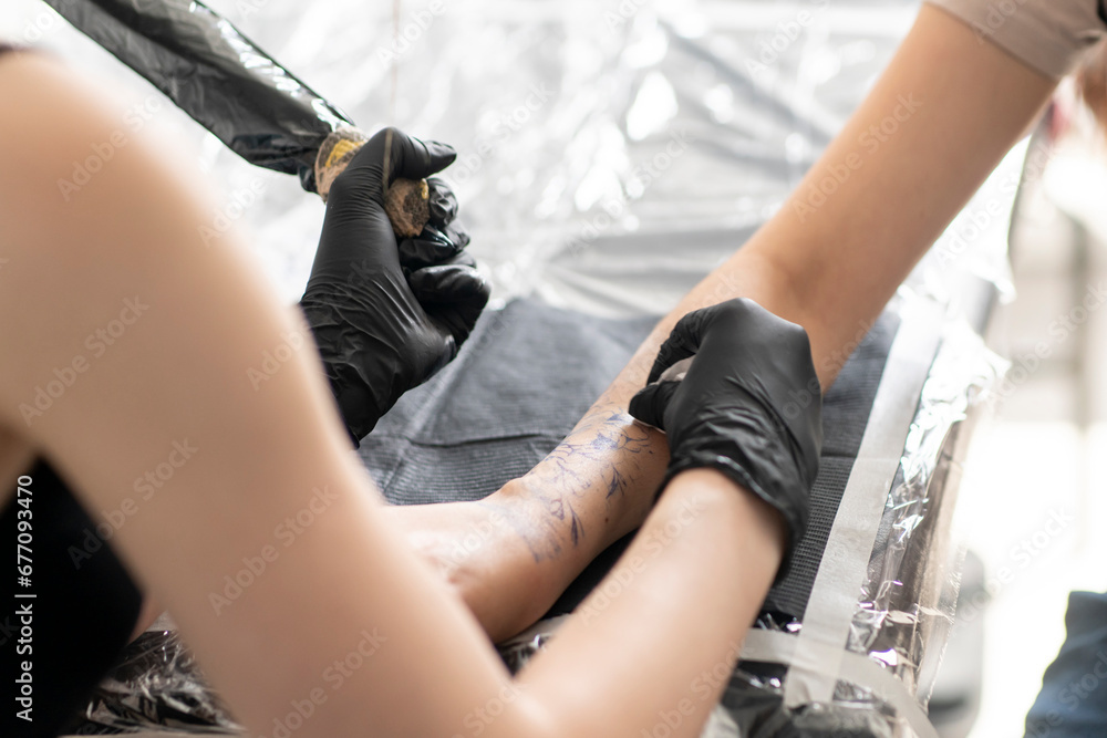 a gorgeous tattoo of a flower on woman's hand, tattoo artist in the process of work