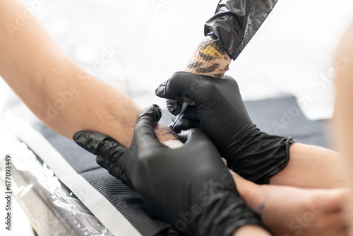 close up female tattoo master making a new flower tattoo using modern new machine photo