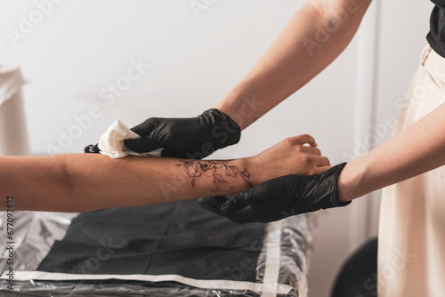 young woman in tattoo studio looking at her new flower tattoo in her arm photo