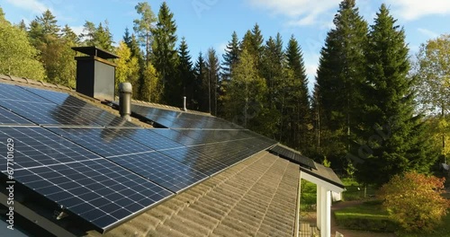 Aerial view low over sunlit solar cells on a house roof, fall evening