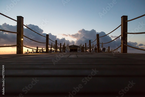 Sunrise over wooden pier ocean.