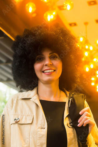 Woman with curly black hair illuminated by yellow lamp.