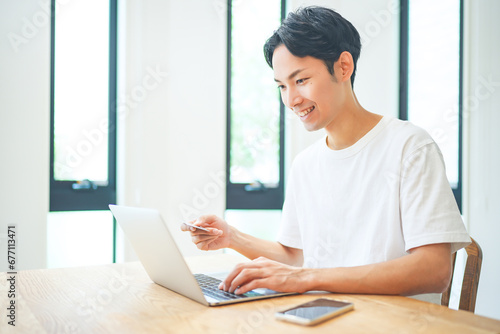 ノートパソコンでクレジットカード決済をする若い男性