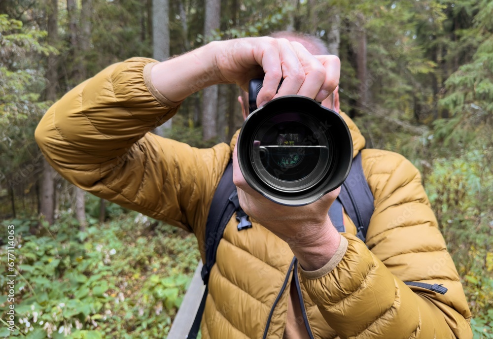 Fototapeta premium Man photographer taking photo in nature, view on lens