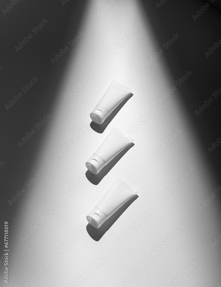 Small cream tubes, packages, containers for cosmetic products in light beam Small cream tubes, packages, containers for cosmetic products in light beam