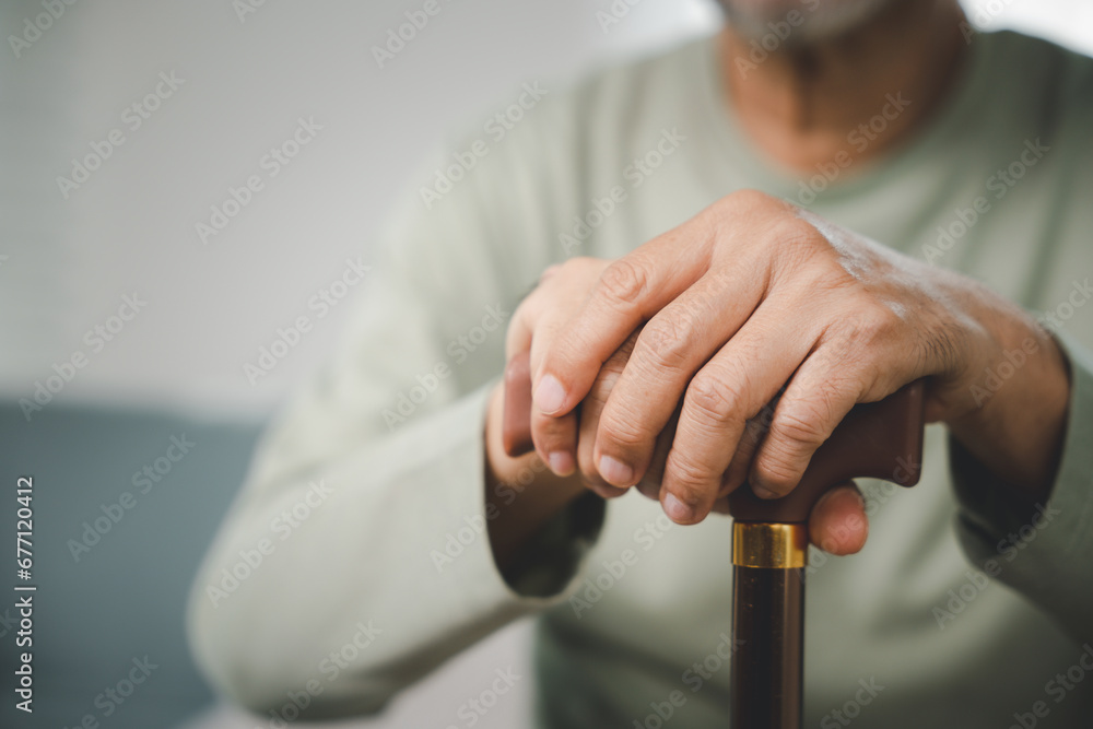 Close up hands of Asian Elderly hand holding handle of cane, senior disabled man holding walking stick, Old man sitting resting at home hold wooden walking cane, International Day for the Elderly Close up hands of Asian Elderly hand holding handle of cane, senior disabled man holding walking stick, Old man sitting resting at home hold wooden walking cane, International Day for the Elderly