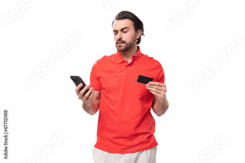 a young brutal 35 year old european man with a well-groomed haircut and a beard in a red t-shirt uses online payments from a smartphone