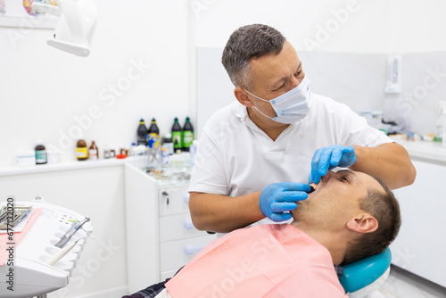 Dentist checking patient's teeth using braces in dental clinic. Medicine, dentistry concept. Dental equipment