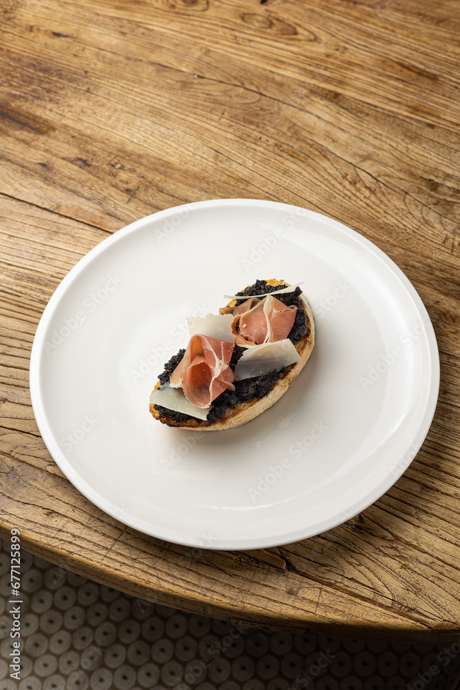 Tasty bruschetta with jamon and cheese on a wooden table Tasty bruschetta with jamon and cheese on a wooden table