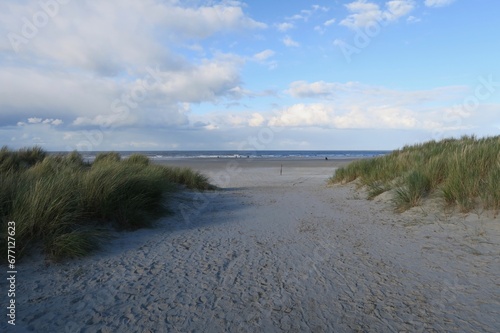 Blick vom sandigen Dünenweg auf der Nordseeinsel Schiermonnikoog auf den breiten Sandstrand und die Nordsee.
