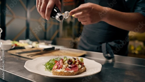 close-up A chef holds a bottle of balsamic vinegar and dresses a bruschetta with it in the kitchen of an Italian restaurant