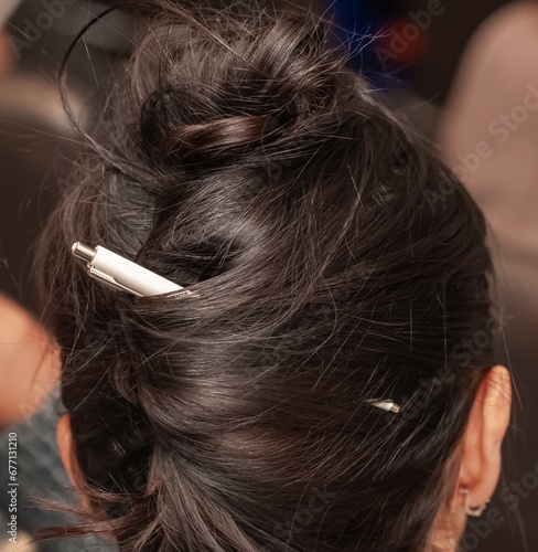 Pen in a woman's hairstyle close-up