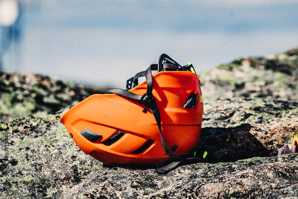 Orange climbing helmet lying on a rock. Orange climbing helmet lying on a rock.