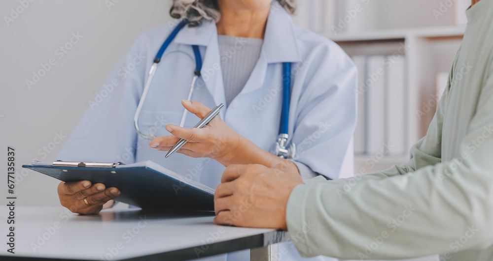 Mature Asian male doctor talking with his patient, explaining the procedure to old lady. Mature Asian male doctor talking with his patient, explaining the procedure to old lady.