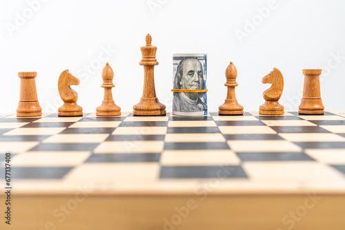 Chess board with one line of white figures, American banknotes rolled and placed instead of white queen. Concept of business strategy, dollar leadership, stock market and unfair competition.