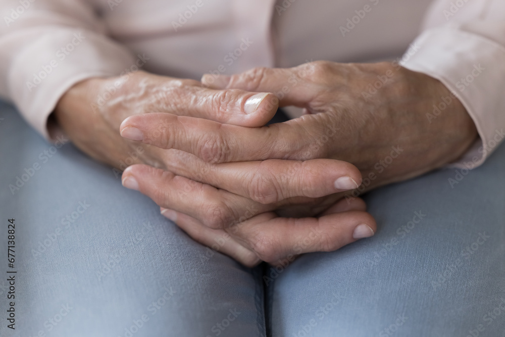 Close up of old woman hands folded on laps sitting indoors, feels lonely, desperate or anxious at nursing home, health problem, make difficult decision. Geriatric medicine, old person, mental disorder