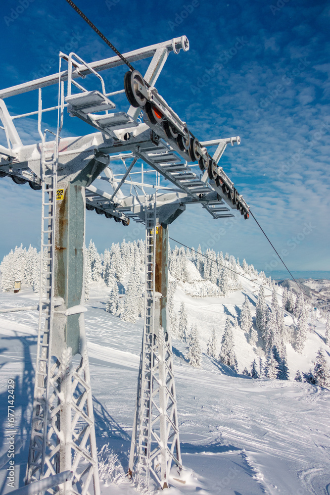 Fototapeta premium Schneebedeckter Skiliftmast an einem sonnigen Wintertag