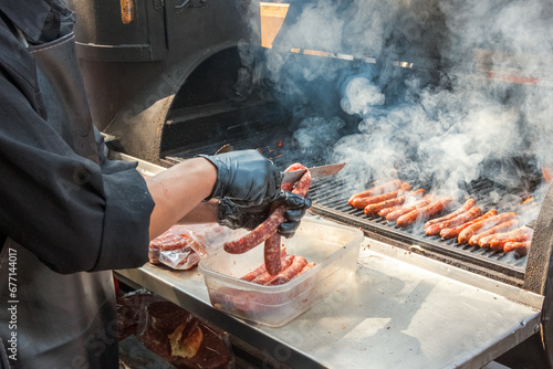 Fototapeta Naklejka Na Ścianę i Meble -  Process of preparing hot dog sausages on a grill with burning coals. Street eatery