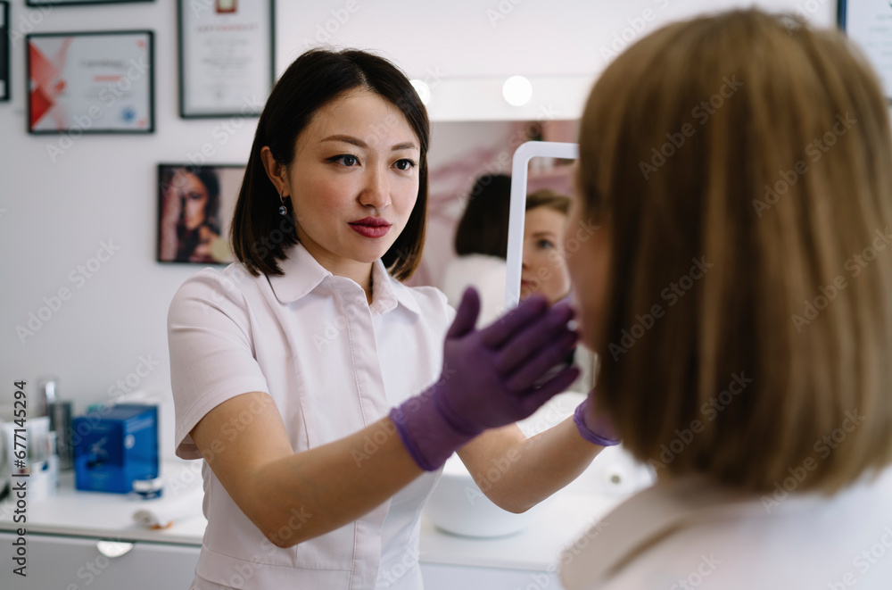 Concentrated female beautician looking at face of client Concentrated female beautician looking at face of client