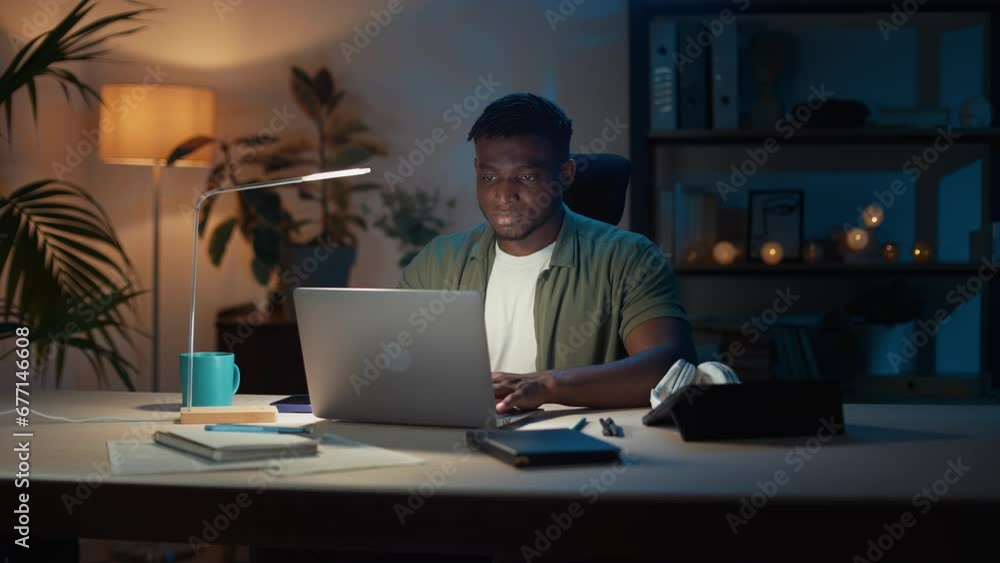 Attentive man working on laptop at home office in evening Attentive man working on laptop at home office in evening