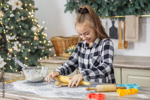 Child girl cooking Christmas gingerbread cookies in cozy home kitchen. Family traditions.