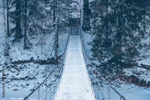 Beautiful rope hanging wooden bridge over the river. winter landscape © iloli