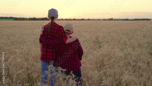Boy son gently hugs his mother at sunset in wheat field. Farmer mother hugging her Child son outdoor. Meeting with sons mother in nature. Family meeting with mother of child. Happy family hugs in sun © zoteva87