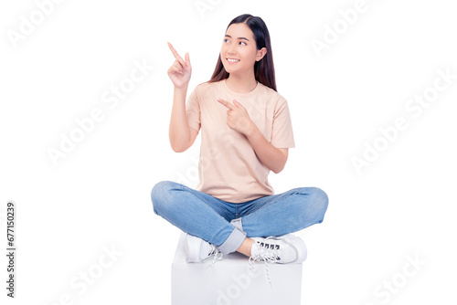 Full body young Asian woman pointing up to copy space and looking at blank space with smile face and happy Pretty girl sit on box chair use for advertising with isolated on white background