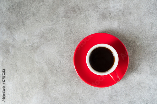 Top view red doppio normale ceramic 80ml or 2oz espresso cup with saucer placed on loft industrial style old cement dining table with copyspace, the black espresso coffee is in the cup. photo