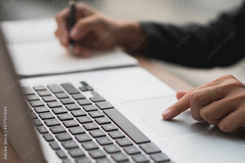 Woman working on laptop at wooden table in office, closeup Woman working on laptop at wooden table in office, closeup