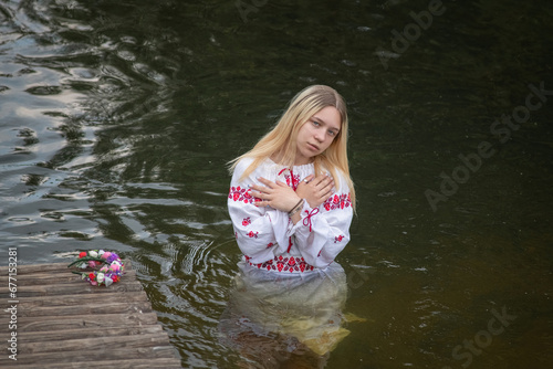 Fototapeta Naklejka Na Ścianę i Meble -  A young beautiful blonde girl in a national costume in the river.