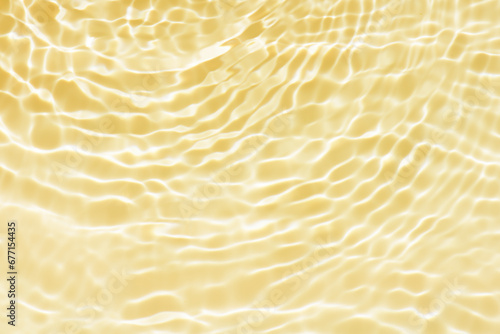 Defocus blurred transparent gold colored clear calm water surface texture with splashes reflection. Trendy abstract nature background. Water waves in sunlight with copy space. Gold watercolor shine.