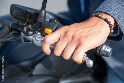 Caucasian man rides an electric motorcycle. Close-up of a man's hand pressing the brake on the steering wheel. 