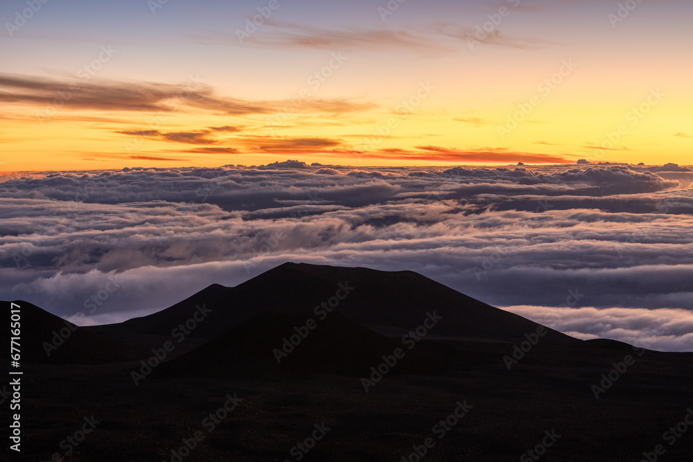 Sunrise view of mountain on Mauna Kea volcano sea of clouds in morning sun