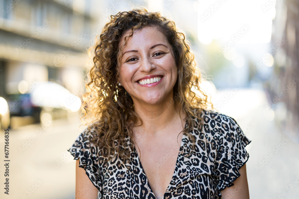 Portrait of a smiling young woman with curly hair in the city
Portrait of a smiling young woman with curly hair in the city