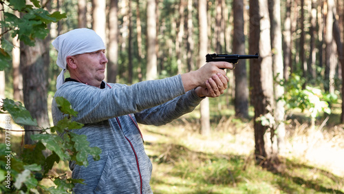 A middle aged man learns to aim from a co2 air pistol. photo