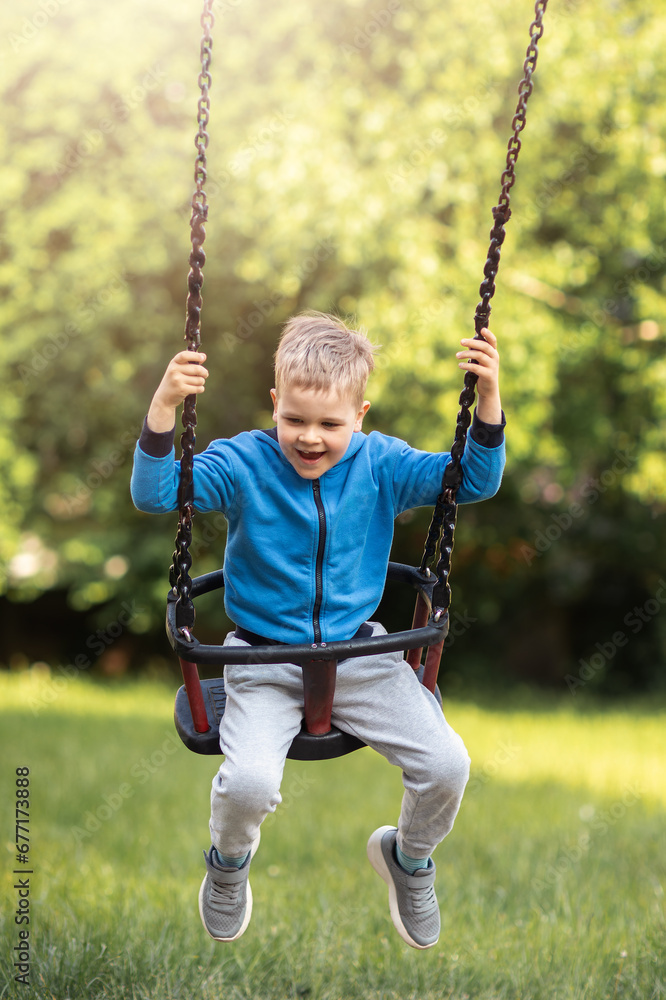 Swinging little boy expression, summer in the yard, sunny blurred background of green trees. Swinging little boy expression, summer in the yard, sunny blurred background of green trees.