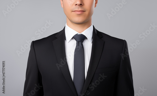 Man in a black suit, white shirt and black tie isolated on a gray background. Young top manager in a business suit photo
